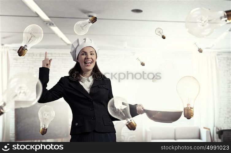 She is going to cook her idea. Pretty businesswoman in suit and cook hat with pan in hand