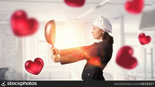 She is going to cook love. Pretty businesswoman in suit and cook hat with pan in hand