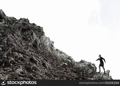 She is going to reach the top. Young determined businesswoman climbing up mountain to reach top