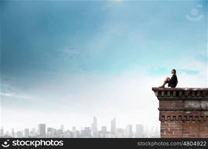 She is in dispair and isolation. Bored young businesswoman sitting alone on building top