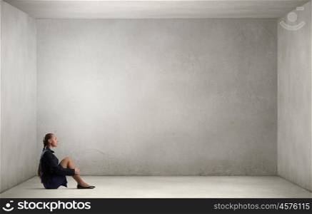 She is in dispair and isolation. Bored young businesswoman sitting alone on floor