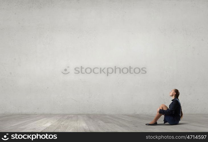 She is in dispair and isolation. Bored young businesswoman sitting alone on floor