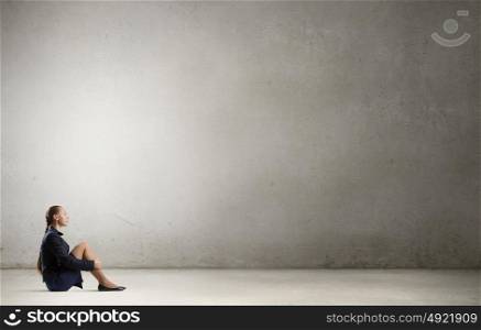 She is in dispair and isolation. Bored young businesswoman sitting alone on floor