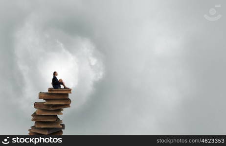 She is in dispair and isolation. Bored young businesswoman sitting alone on pile of books