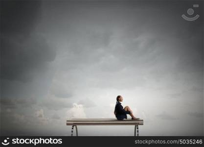She is in dispair and isolation. Bored young businesswoman sitting alone on wooden bench
