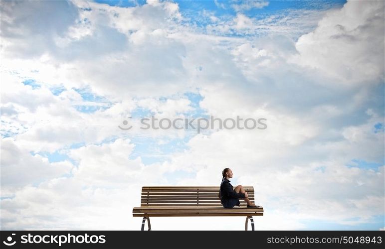 She is in dispair and isolation. Bored young businesswoman sitting alone on wooden bench