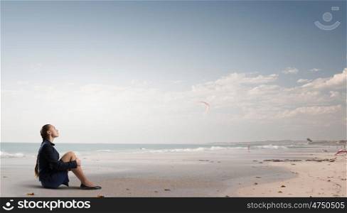 She is in dispair and isolation. Thoughtful young businesswoman sitting alone on ocean coast