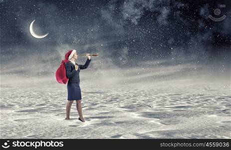 She is looking forward Christmas. Woman in formal suit and Santa hat looking in spyglass