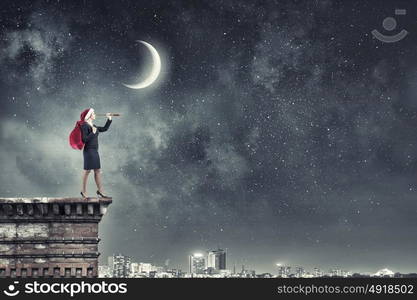 She is looking forward Christmas. Woman in formal suit and Santa hat looking in spyglass