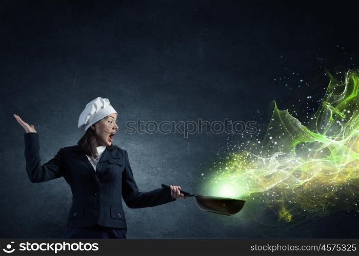 She is magician as cook. Attractive woman chef in suit with pan in hand