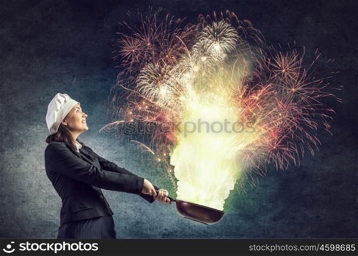 She is magician as cook. Attractive woman chef in suit with pan in hand