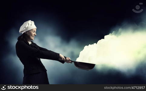 She is magician as cook. Attractive woman chef in suit with pan in hand