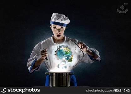 She is magician as cook. Pretty woman cook in hat and apron with doing magic above pot. Elements of this image are furnished by NASA