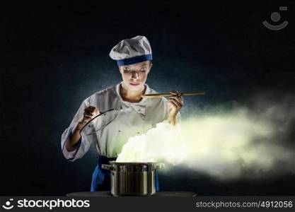 She is magician as cook. Pretty woman cook in hat and apron opening pot