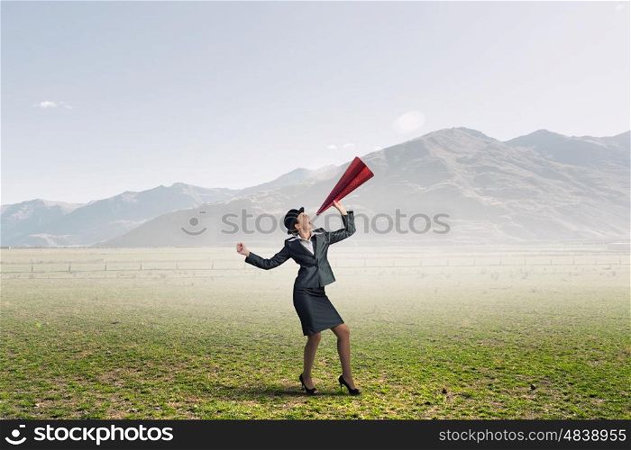 She is making announcement. Young woman in suit and bowler hat screaming in paper trumpet