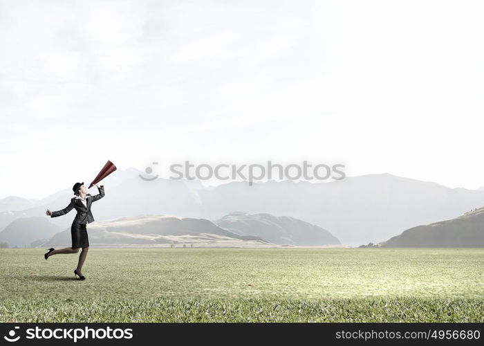 She is making announcement. Young woman in suit and bowler hat screaming in paper trumpet