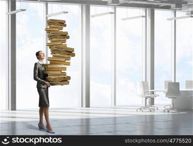 She is mastering the science. Young businesswoman carrying pile of old books