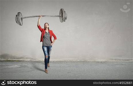 She is powerful and determined. Young woman in red jacket lifting barbell above head