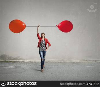 She is powerful and determined. Young woman in red jacket lifting barbell in one hand