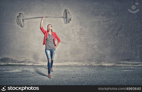 She is powerful and determined. Young woman in red jacket lifting barbell in one hand