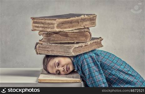 She is preparing for exams. Student girl pressed with pile of books to table