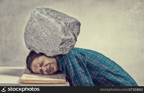 She is preparing for exams. Student girl pressed with stone to opened book pages