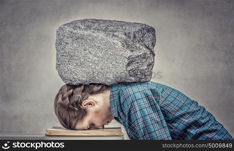 She is preparing for exams. Student girl pressed with stone to opened book pages