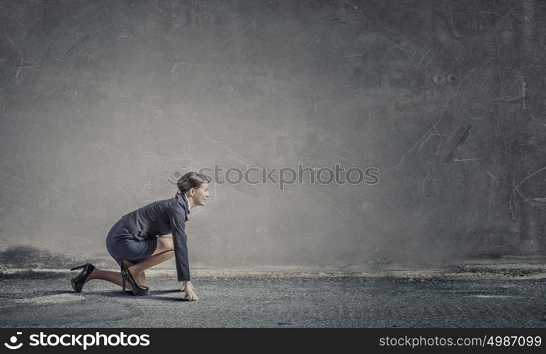 She is ready to challege it. Young determined businesswoman standing in start position ready to compete