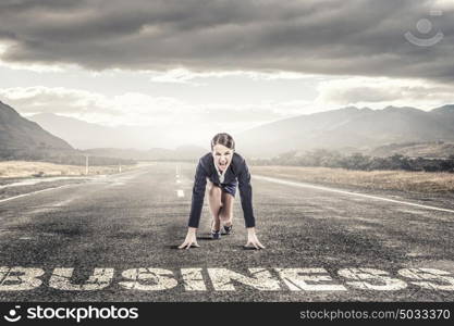 She is ready to challege it. Young determined businesswoman standing in start position ready to compete