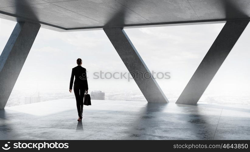 She is ready to face new day. Businesswoman with suitcase in modern interior looking in office window