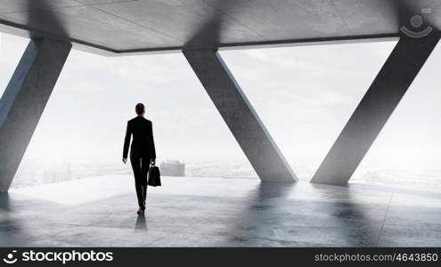 She is ready to face new day. Businesswoman with suitcase in modern interior looking in office window