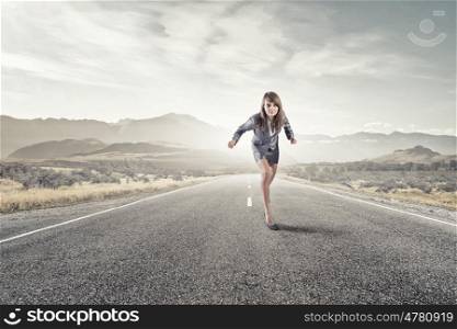 She is ready to run this race. Young determined businesswoman on road standing in start position