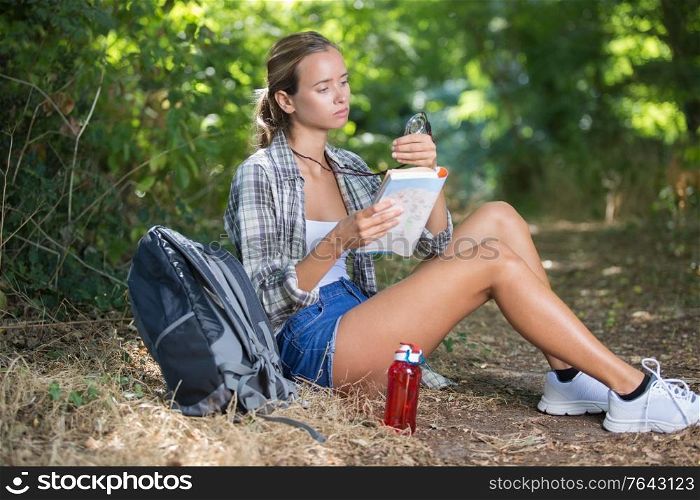 she is sitting under a tree and reading a map