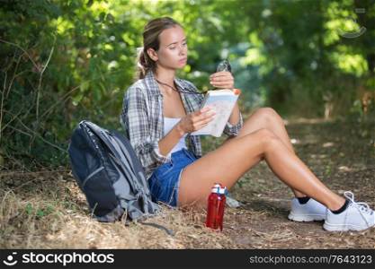 she is sitting under a tree and reading a map