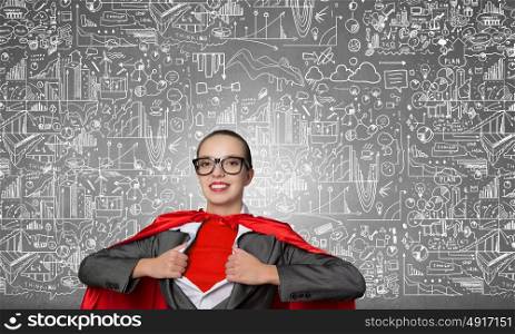 She is super financier. Young businesswoman in red cape acting like super hero and sketches on background