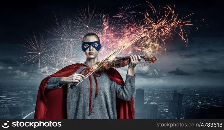 She is super violinist. Young confident woman in red cape and mask play violin