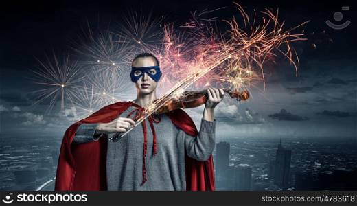 She is super violinist. Young confident woman in red cape and mask play violin