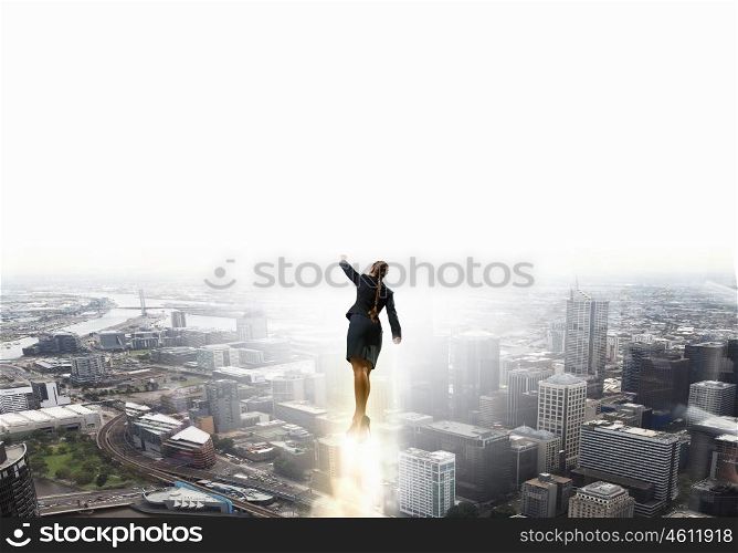 She is super woman. Businesswoman hero in suit flying up into sky above city