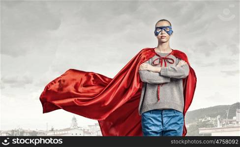 She is super woman. Young confident woman in red cape and mask