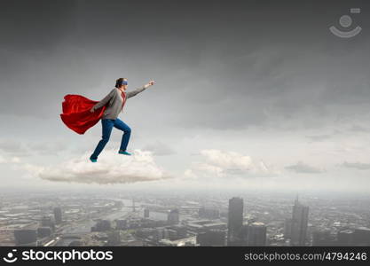 She is super woman. Young confident woman in red cape and mask