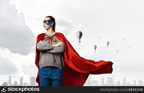 She is super woman. Young confident woman in red cape and mask