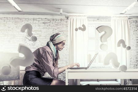 She is surfing the Internet. Young hipster girl sitting at table and working on laptop