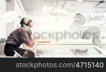 She is surfing the Internet. Young hipster girl sitting at table and working on laptop