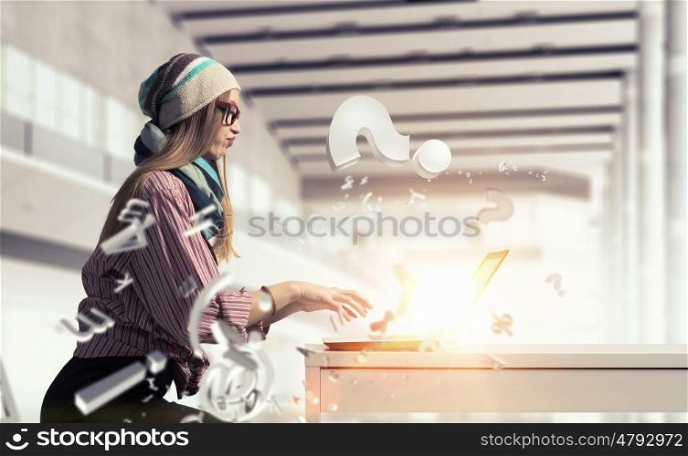 She is surfing the Internet. Young hipster girl sitting at table and working on laptop