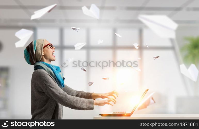 She is surfing the Internet. Young hipster girl sitting at table and working on laptop