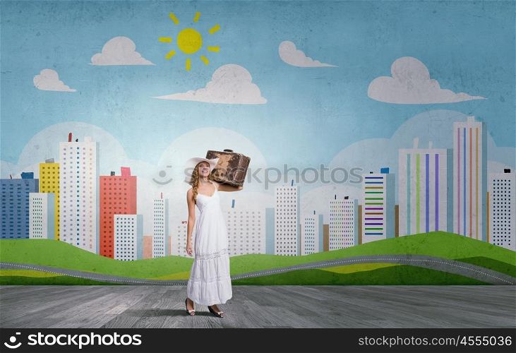 She is traveling light. Woman with suitcase in white long dress and hat