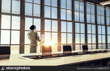 She is working till sundown. Mixed media. Elegant businesswoman in office in light of sunset