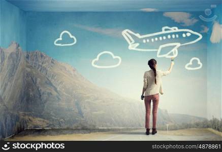She likes traveling. Young girl standing with back and drawing airplane on wall
