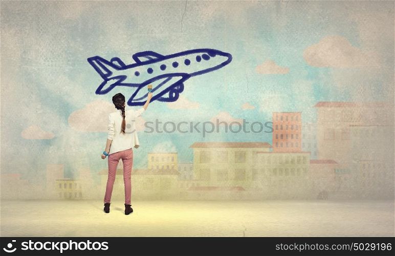 She likes traveling. Young girl standing with back and drawing airplane on wall