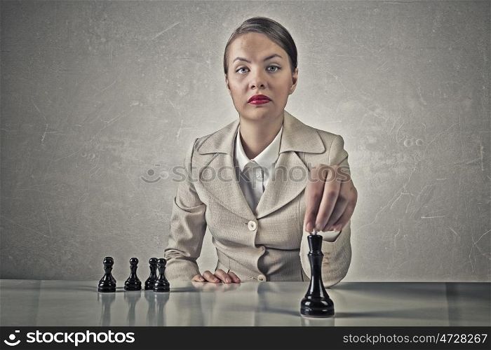 She plays her strategy. Young pretty businesswoman sitting at table and playing chess